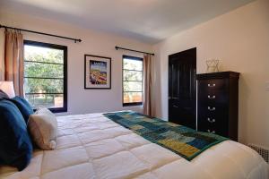 a bedroom with a large bed with a dresser and two windows at West Beach Villa 4 in Santa Barbara