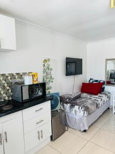 Habitación pequeña con cama y microondas. en Mila Lodge 2, en Ciudad del Cabo