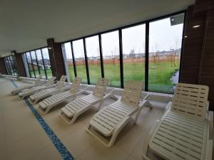 a row of white chairs in a room with windows at Apolonia apartamenty I - SPA in Dziwnów