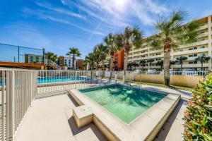 a swimming pool with a building and palm trees at Surf Dweller 509 in Fort Walton Beach