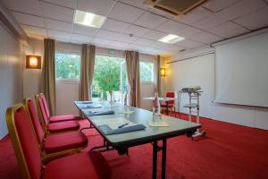 une salle de conférence avec une grande table et des chaises rouges dans l'établissement Kyriad Nantes Sud - Bouaye Aéroport, à Bouaye