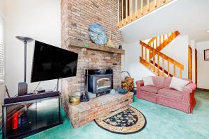 a living room with a brick fireplace with a tv at A Very Vermont Vacation in Jamaica