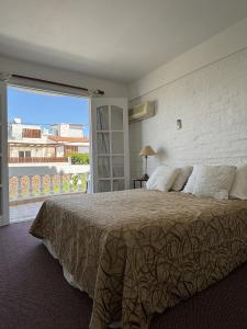 a bedroom with a large bed and a large window at Bagu Villa de Mar in Punta del Este