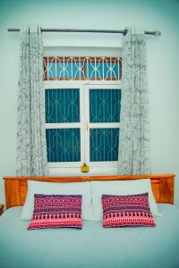 a bed with two pillows in front of a window at Zanzibar Spice Hut Apartment in Stone Town
