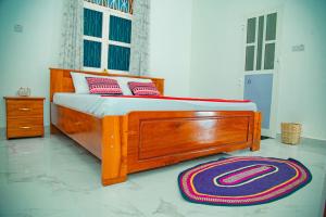 a wooden bed in a bedroom with a rug at Zanzibar Spice Hut Apartment in Stone Town