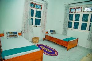 two beds in a room with windows and a rug at Zanzibar Spice Hut Apartment in Stone Town