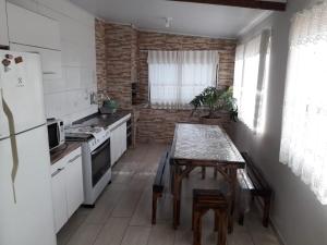 a kitchen with a table and a white refrigerator at Casa do Henrique 1 in Sorocaba