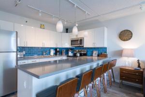 a kitchen with a long counter with chairs in it at Waikiki Banyan Ohana Suite in Honolulu