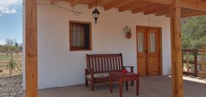 a porch with a wooden chair and a table at Cabaña "Amanecer" in Chilecito