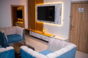 a living room with two chairs and a tv at Dozubel Hotel in Abuja