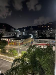 um horizonte da cidade à noite com um parque de estacionamento em Lindo apto 3 qtos, a 350 mtrs praia da enseada com serviço de praia e portaria 24 hrs próx casa grande hotel, hipermercados, farmácias bancos no Guarujá