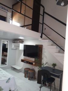 ein Wohnzimmer mit einem TV und einer Treppe in der Unterkunft Casa do Henrique 3 in Sorocaba