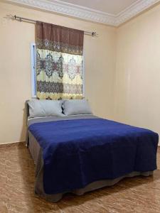 a bedroom with a blue bed with a window at Saffy Guest House in Brikama