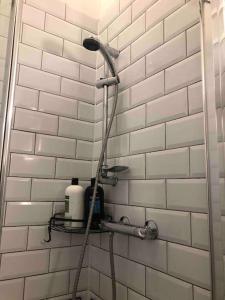 a shower in a bathroom with a white tiled wall at Very Nice Flat close to Camden Station in London