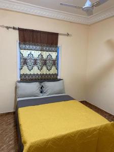 a bedroom with a yellow bed with a window at Saffy Guest House in Brikama