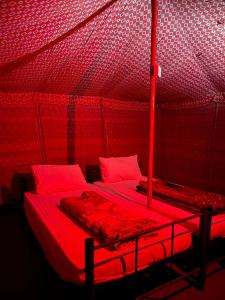 a red room with two beds in a tent at SandGlass Camp in Bidiyah