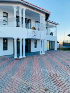 a large white building with a brick driveway at Ngqamakwe Luxury Guest House and Conference Centre in Nqamakwe