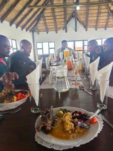 a group of people sitting around a table with food at Ngqamakwe Luxury Guest House and Conference Centre in Nqamakwe