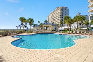 a swimming pool with chairs and a building at Beach Club Avalon 1204 in Gulf Highlands