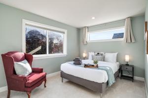 a bedroom with a bed and a chair and two windows at Phinney Guest House BY Betterstay in Seattle