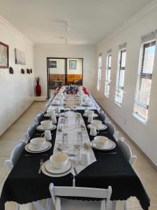 a long dining room with a long table with plates and dishes at Ngqamakwe Luxury Guest House and Conference Centre in Nqamakwe