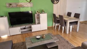 a living room with a television and a table with chairs at Finans1 in Ruma