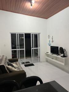 een woonkamer met een bank en een tv bij PARAISO DAS AGUAS - CHALÉ in Barra de Santo Antônio