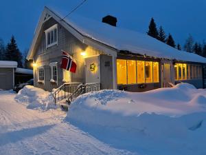 a house covered in snow with a pile of snow at Søre Osen Ørbekken in Midskogberget