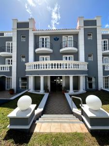 a large building with two white benches in front of it at Bagu Villa de Mar in Punta del Este