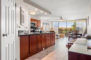 a kitchen with wooden cabinets and a living room at Maui Sunset A513 BY Betterstay in Kihei