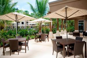朱庇特的住宿－朱庇特棕櫚灘萬怡酒店，一个带桌椅和遮阳伞的庭院