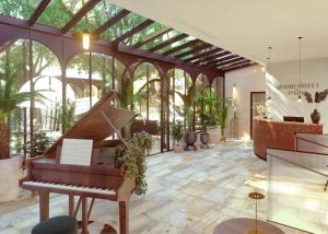 une véranda avec un piano dans une pièce ornée de plantes dans l'établissement Grand Hôtel Du Parc - Teritoria, à Aix-les-Bains