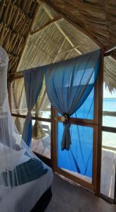 a room with a window with a blue curtain at Cayuco Maya in Bacalar