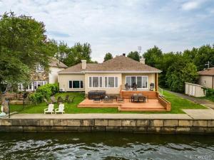 une maison avec une grande terrasse à côté d'une masse d'eau dans l'établissement Modern Lake Champlain Villa with Spa, à Venise-en-Québec