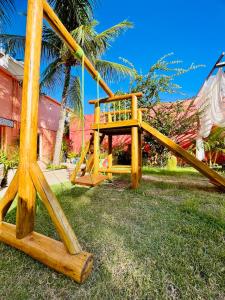 un parque infantil de madera con un tobogán en el césped en Pousada Vila Nalu, en Praia do Frances