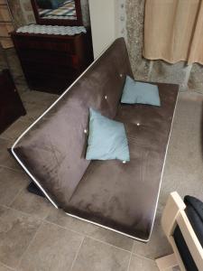 - un canapé brun avec 2 oreillers bleus dans l'établissement Casa das Cortes - Serra da Estrela, à Gouveia