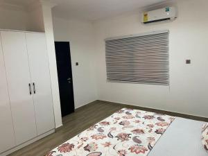a white room with a bed and a window at Cozy 1 Bed Apartment East Legon in Bawaleshi