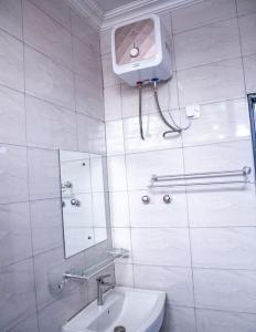 a white bathroom with a sink and a mirror at Cozy 1 Bed Apartment East Legon in Bawaleshi