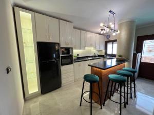 a kitchen with a black refrigerator and some bar stools at Charming 2BR with Private Garden in Cairo