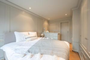 una camera da letto con un grande letto bianco con cuscini bianchi di 7e verdiep Appartement met zeezicht in Knokke voor 6 personen a Knokke-Heist