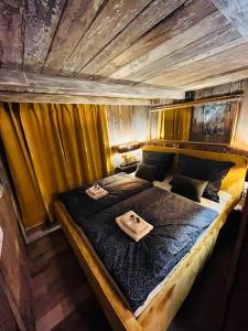 a large bed in a room with yellow curtains at Tiny House Všemily in Jetřichovice