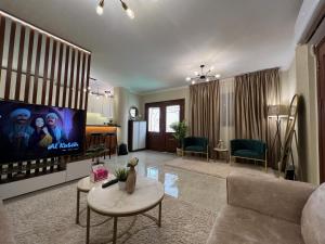 Charming 2BR with Private Garden في القاهرة: غرفة معيشة مع أريكة وتلفزيون بشاشة مسطحة