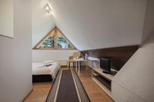 Dormitorio pequeño en el ático con cama y ventana en Pensjonat Arnika, en Zakopane