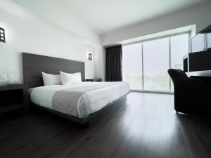 a bedroom with a large bed and a large window at We Hotel Aeropuerto in Mexico City