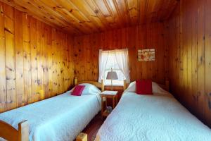two beds in a room with wooden walls at Castine Cottages # 4 in Castine