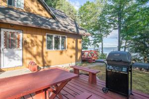 a picnic table and a grill on a wooden deck at Smith Family Cottages- Lake House in Indian River