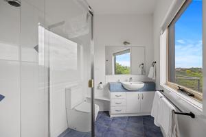 ein Bad mit einem Waschbecken, einem WC und einem Fenster in der Unterkunft Beach Escape Penthouse 2 Bdr Apartment in Sandy Point