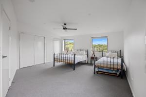a white room with two beds and two windows at Beach Escape Penthouse 2 Bdr Apartment in Sandy Point