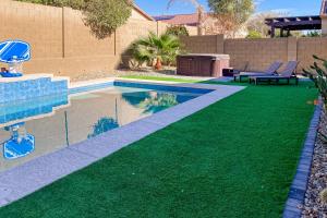 a backyard with a swimming pool and green grass at Sweet Home Sherman in Goodyear