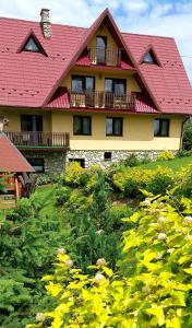 une maison avec un toit rouge et un champ de fleurs dans l'établissement Willa Pośrednia, à Zakopane